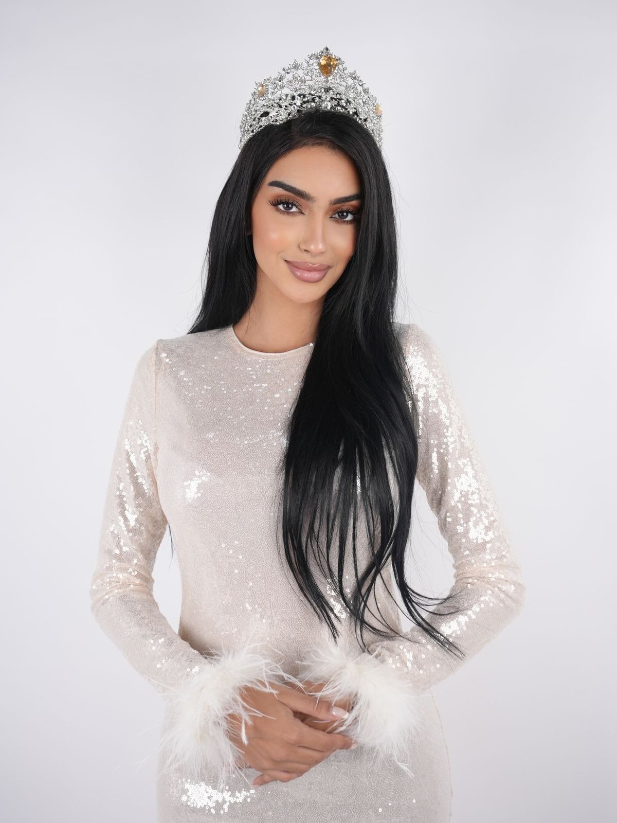 Elegant seated pose with a soft backdrop, highlighting a polished and professional look.